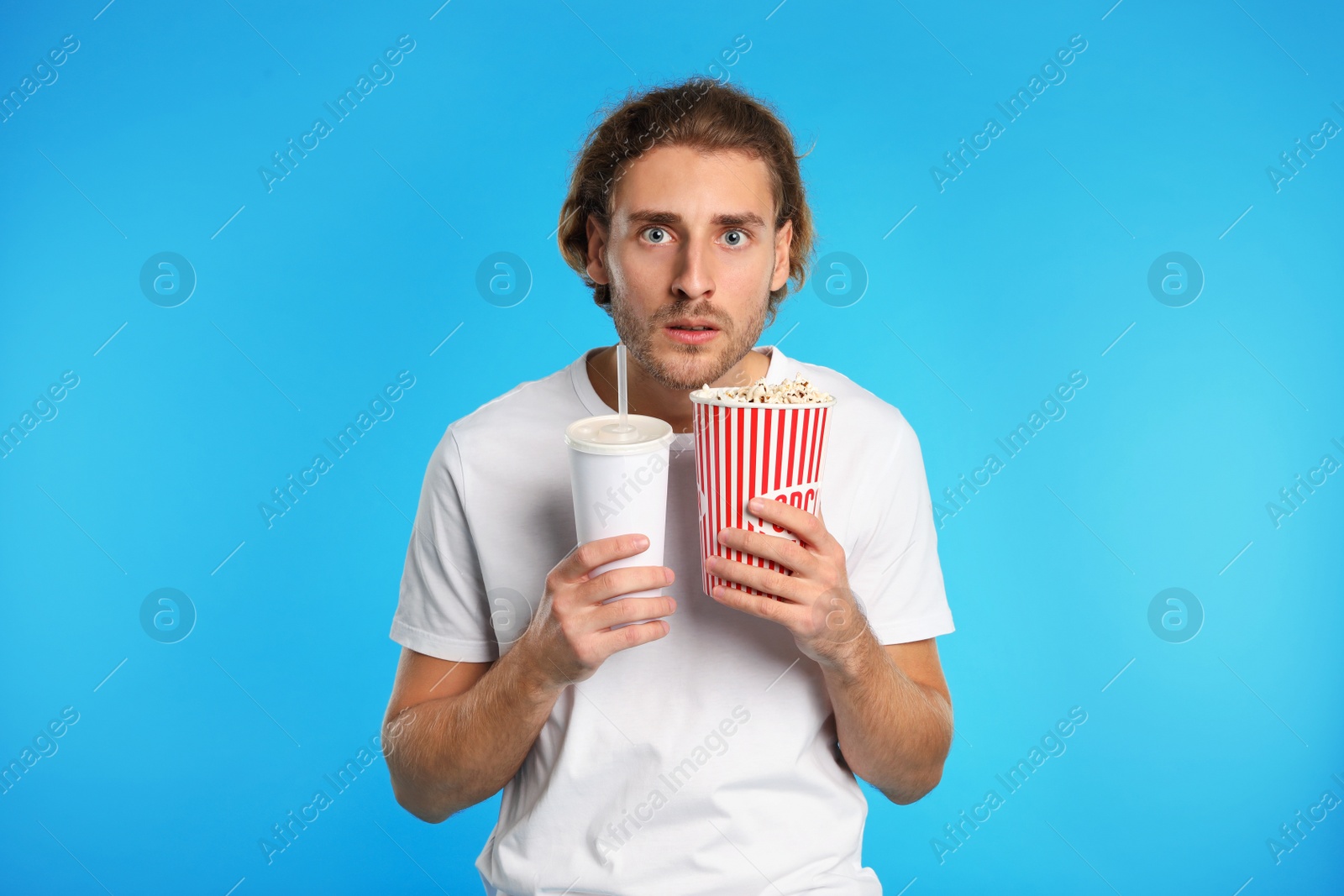 Photo of Emotional man with popcorn and beverage during cinema show on color background