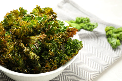 Photo of Tasty baked kale chips in bowl, closeup