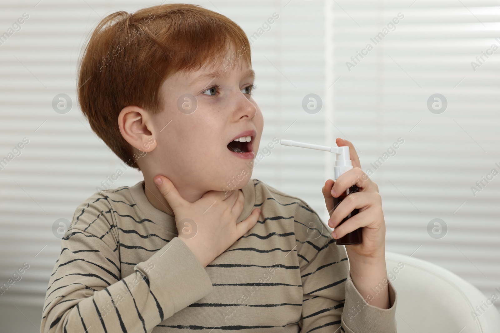 Photo of Little boy using throat spray at home