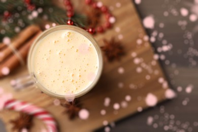 Image of Glass of delicious eggnog on wooden table, flat lay. Bokeh effect