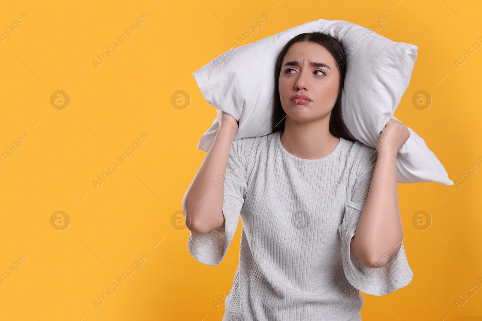 Photo of Tired young woman with pillow on yellow background, space for text. Insomnia problem