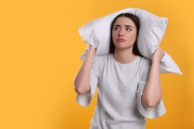 Photo of Tired young woman with pillow on yellow background, space for text. Insomnia problem