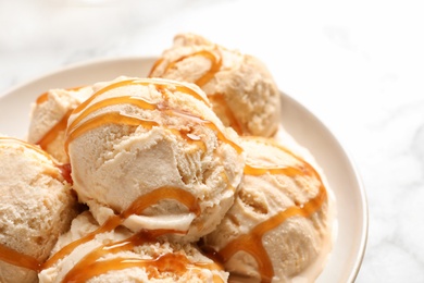 Photo of Tasty ice cream with caramel sauce on plate, closeup