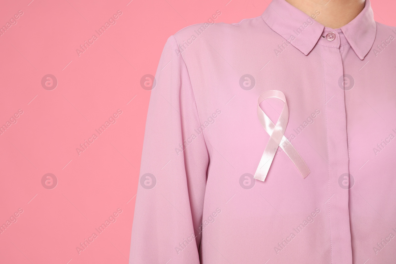 Photo of Closeup view of woman with pink ribbon on color background, space for text. Breast cancer awareness