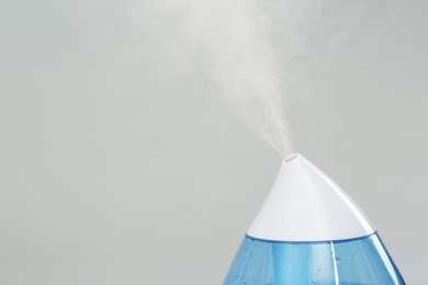 Photo of Modern air humidifier on light grey background, closeup. Space for text