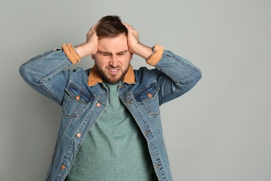 Man suffering from migraine on grey background