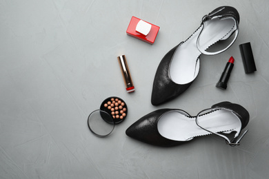 Flat lay composition with stylish shoes and cosmetics on grey table. Space for text