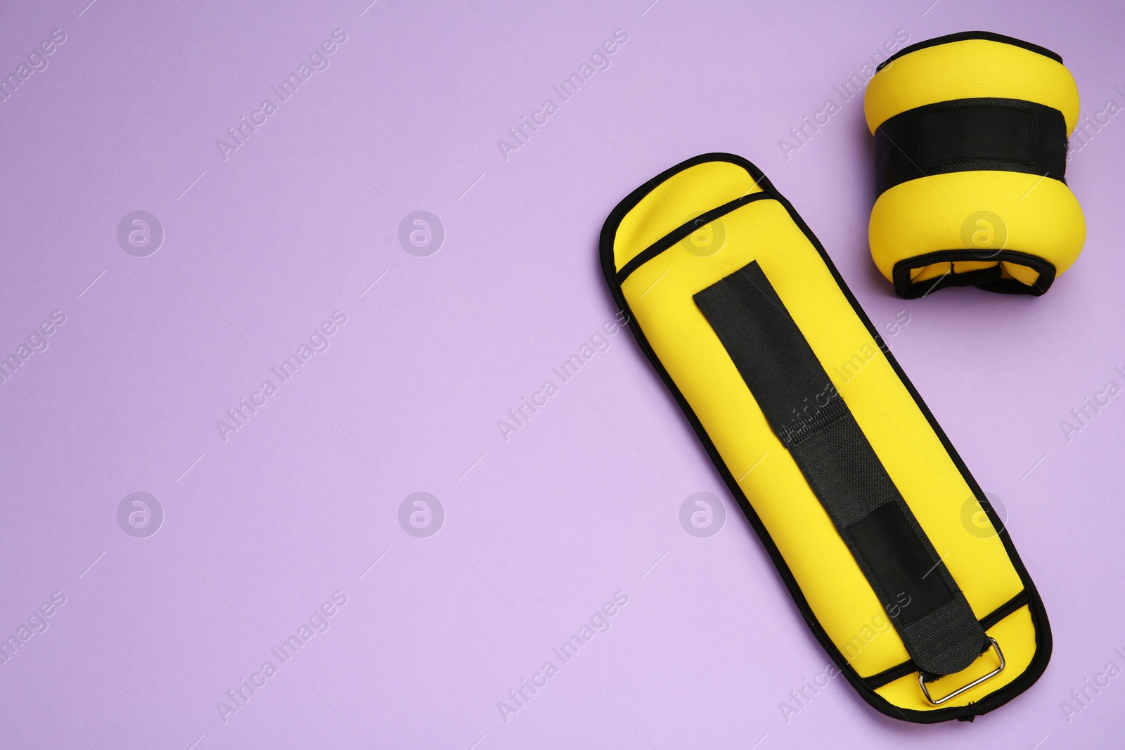 Photo of Yellow weighting agents on violet background, flat lay. Space for text