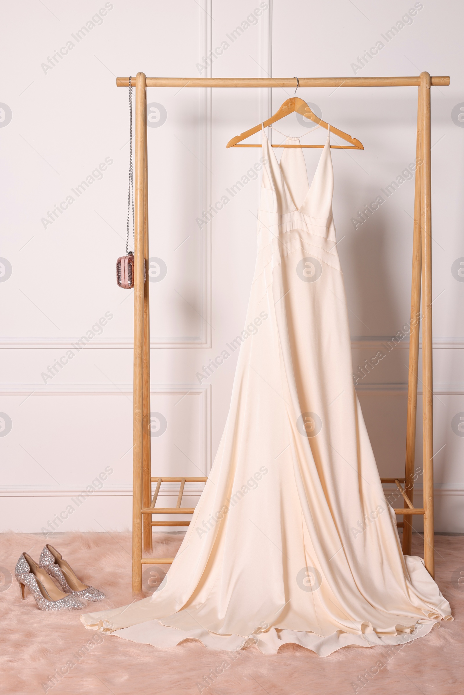 Photo of Rack with wonderful long dress, shoes and clutch in showroom. Preparing for party