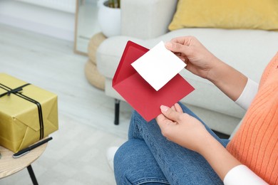 Young woman with greeting card in living room, closeup