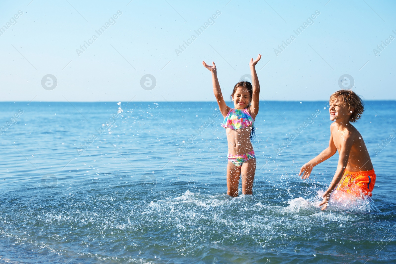 Photo of Cute little children having fun in sea on sunny day. Beach holiday