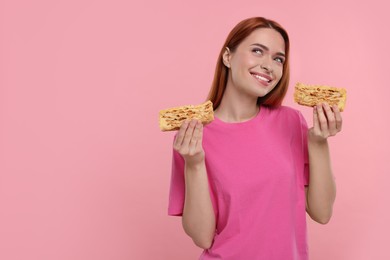 Photo of Young woman with pieces of tasty cake on pink background, space for text