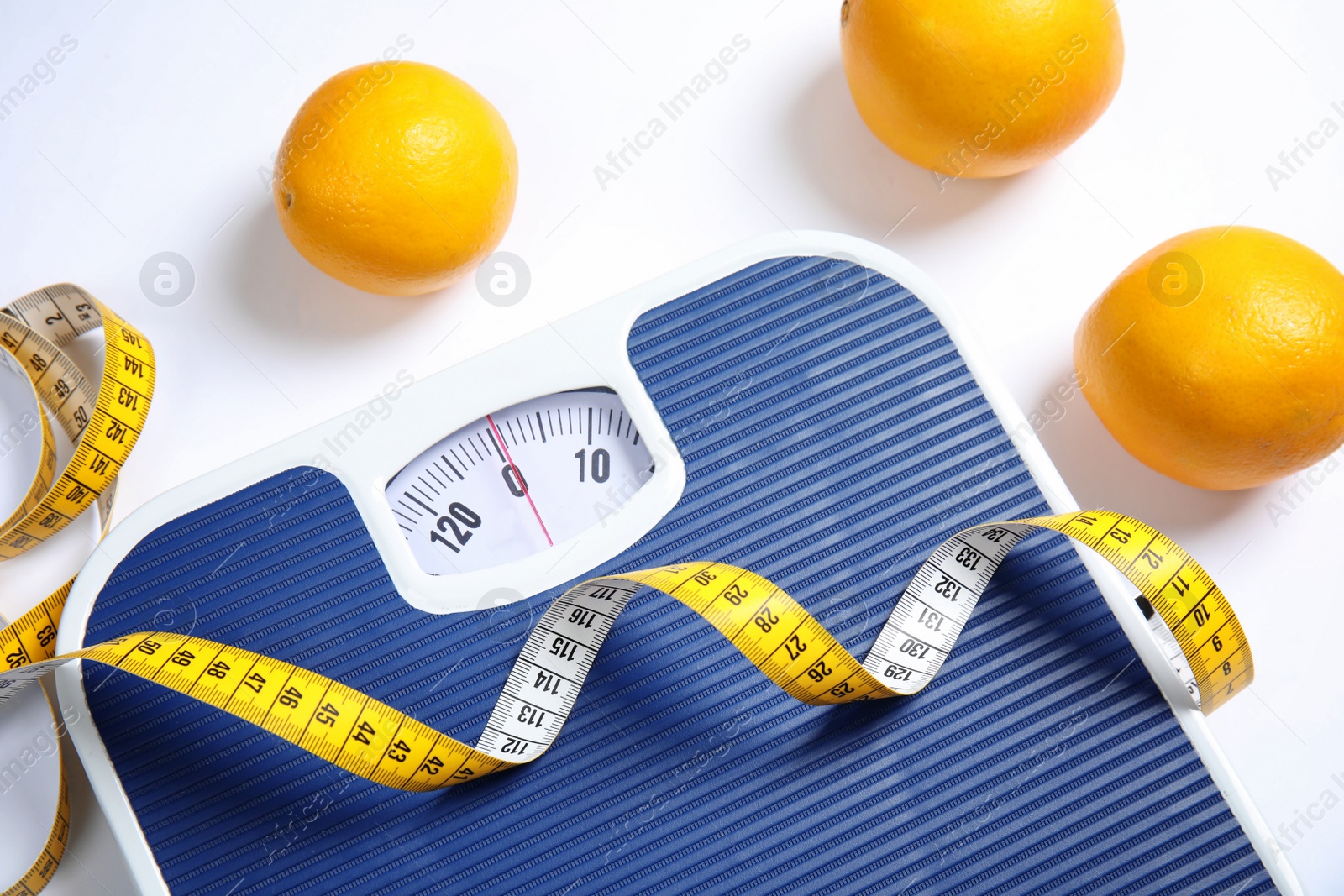 Photo of Modern scales, oranges and tape measure on white background