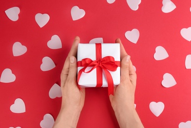 Photo of Woman holding gift box on red background, top view. Valentine's Day celebration