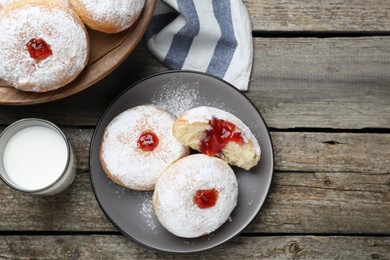 Photo of Delicious jelly donuts served with milk on wooden table, flat lay
