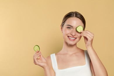 Photo of Young woman with cucumber slices on beige background, space for text. Eye skin care