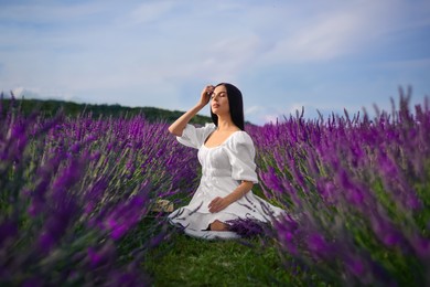 Photo of Beautiful young woman sitting in lavender field