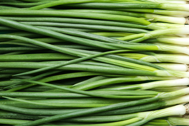 Photo of Fresh green spring onions as background, top view