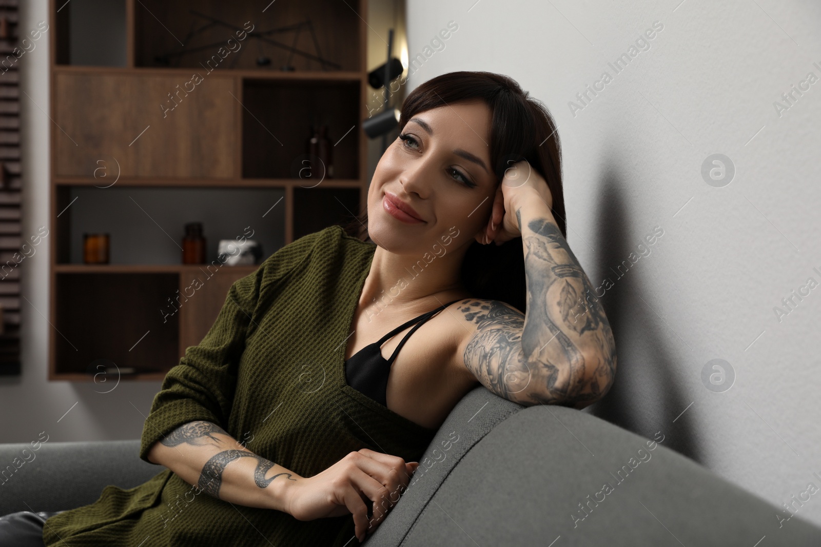 Photo of Beautiful woman with tattoos on arms resting in living room