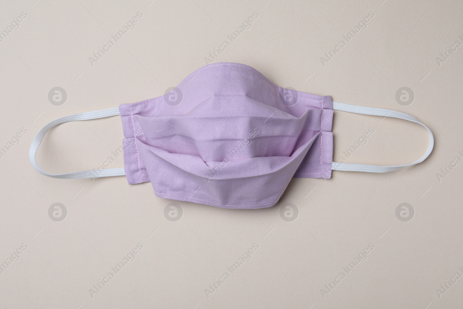 Photo of Homemade protective mask on beige background, top view. Sewing idea