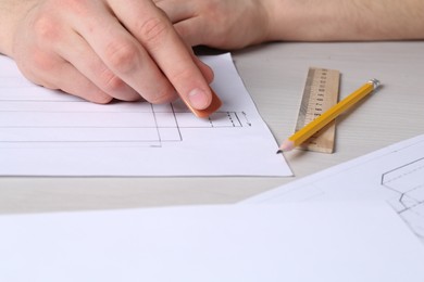 Photo of Man creating packaging design at light wooden table, closeup