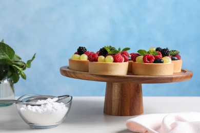 Delicious tartlets with berries on white table