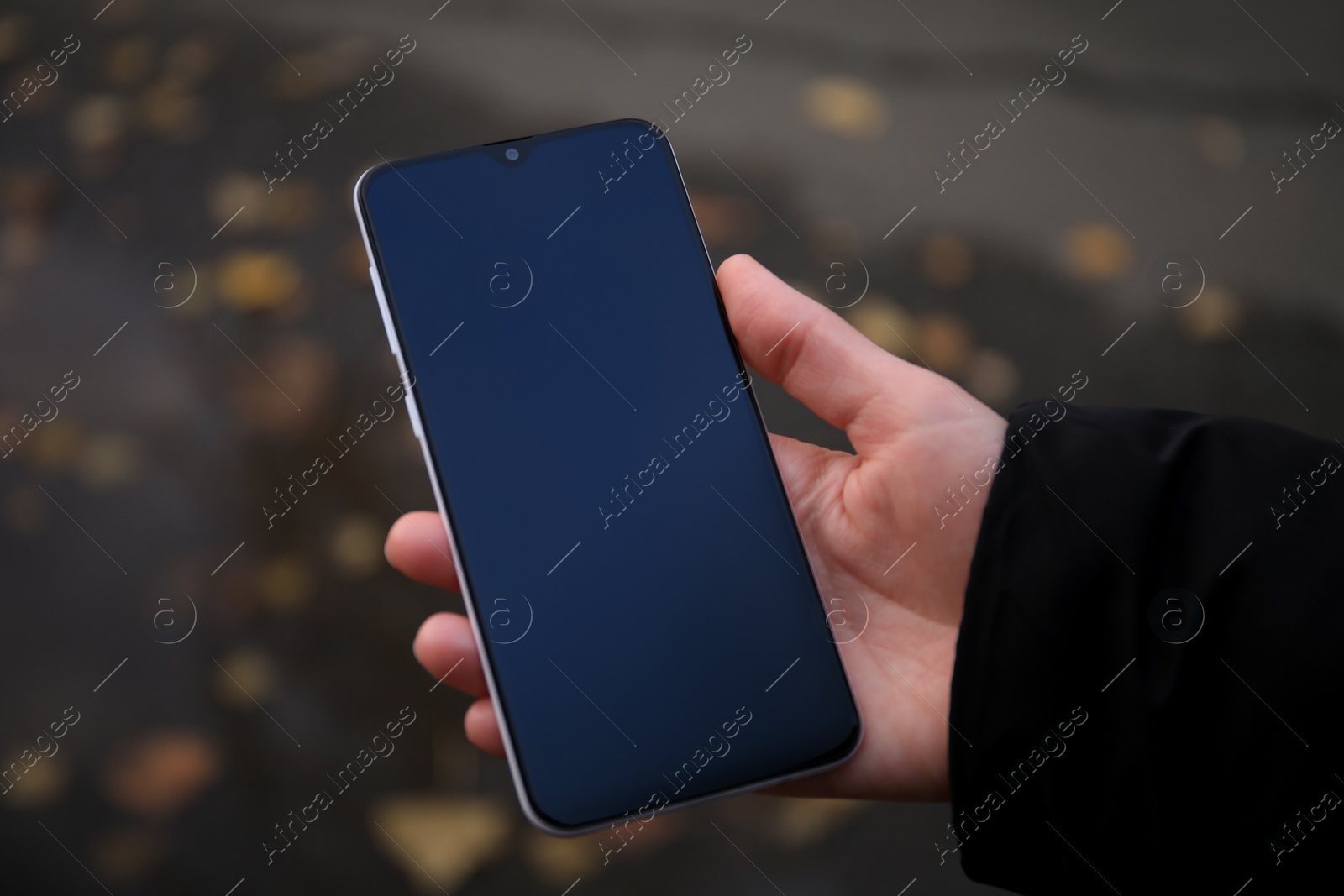 Photo of Woman holding phone outdoors on rainy day, closeup. Space or text