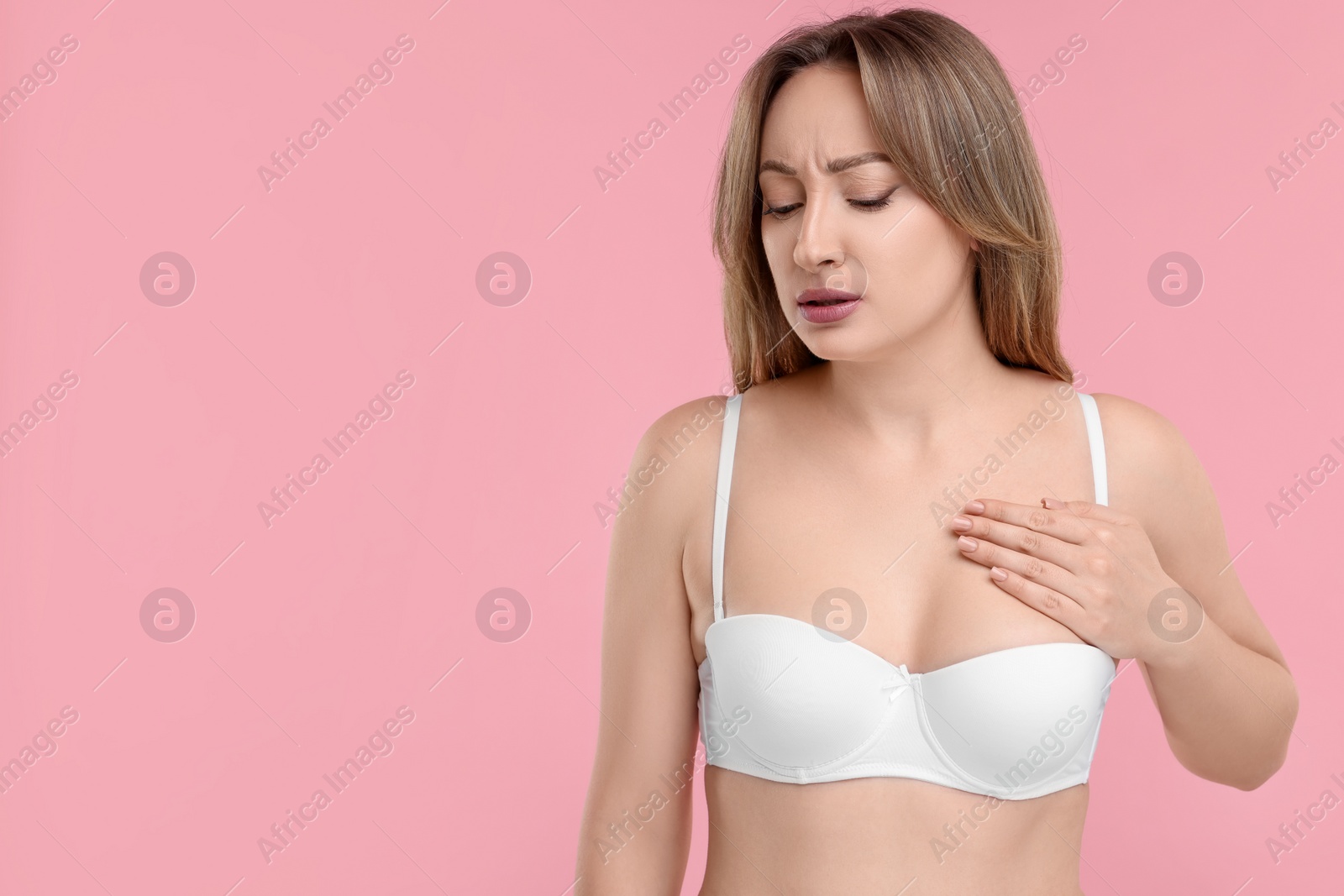 Photo of Mammology. Young woman doing breast self-examination on pink background
