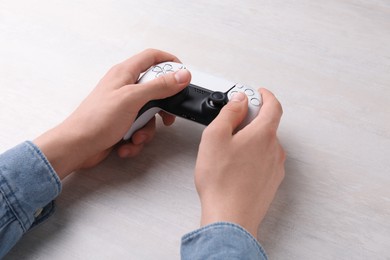 Man using wireless game controller at white table, closeup
