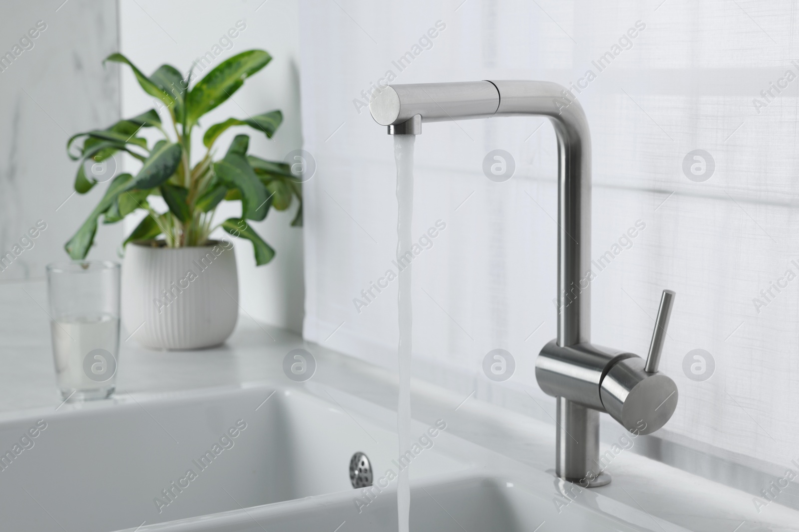 Photo of Stream of water flowing from tap in kitchen