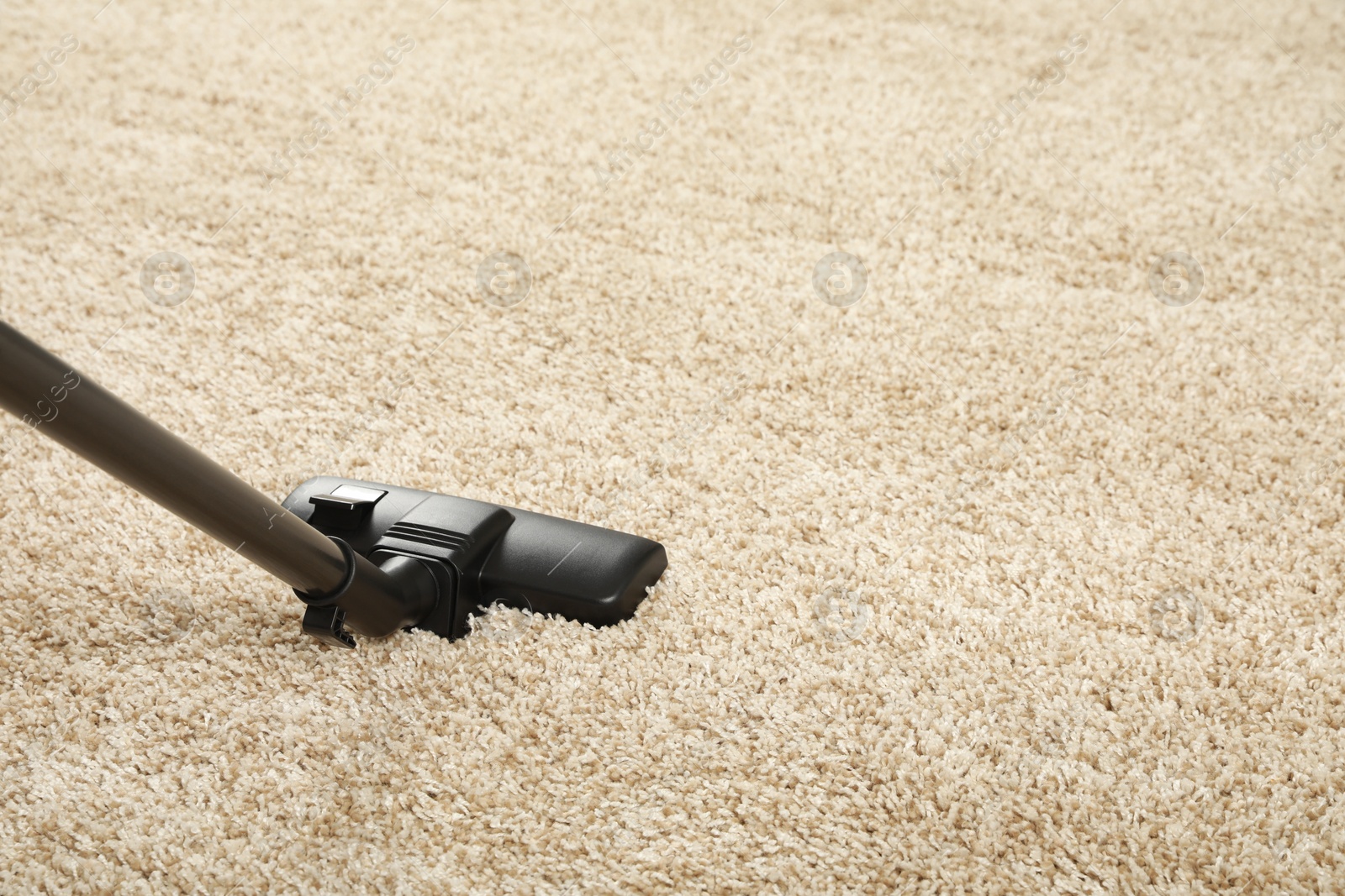 Photo of Removing dirt from beige carpet with modern vacuum cleaner. Space for text