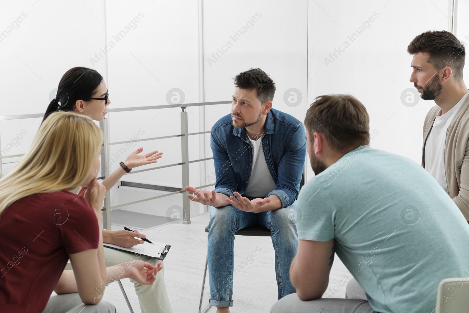 Photo of Psychotherapist working with group of drug addicted people at therapy session indoors