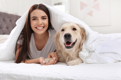 Photo of Young woman and her Golden Retriever dog on bed at home