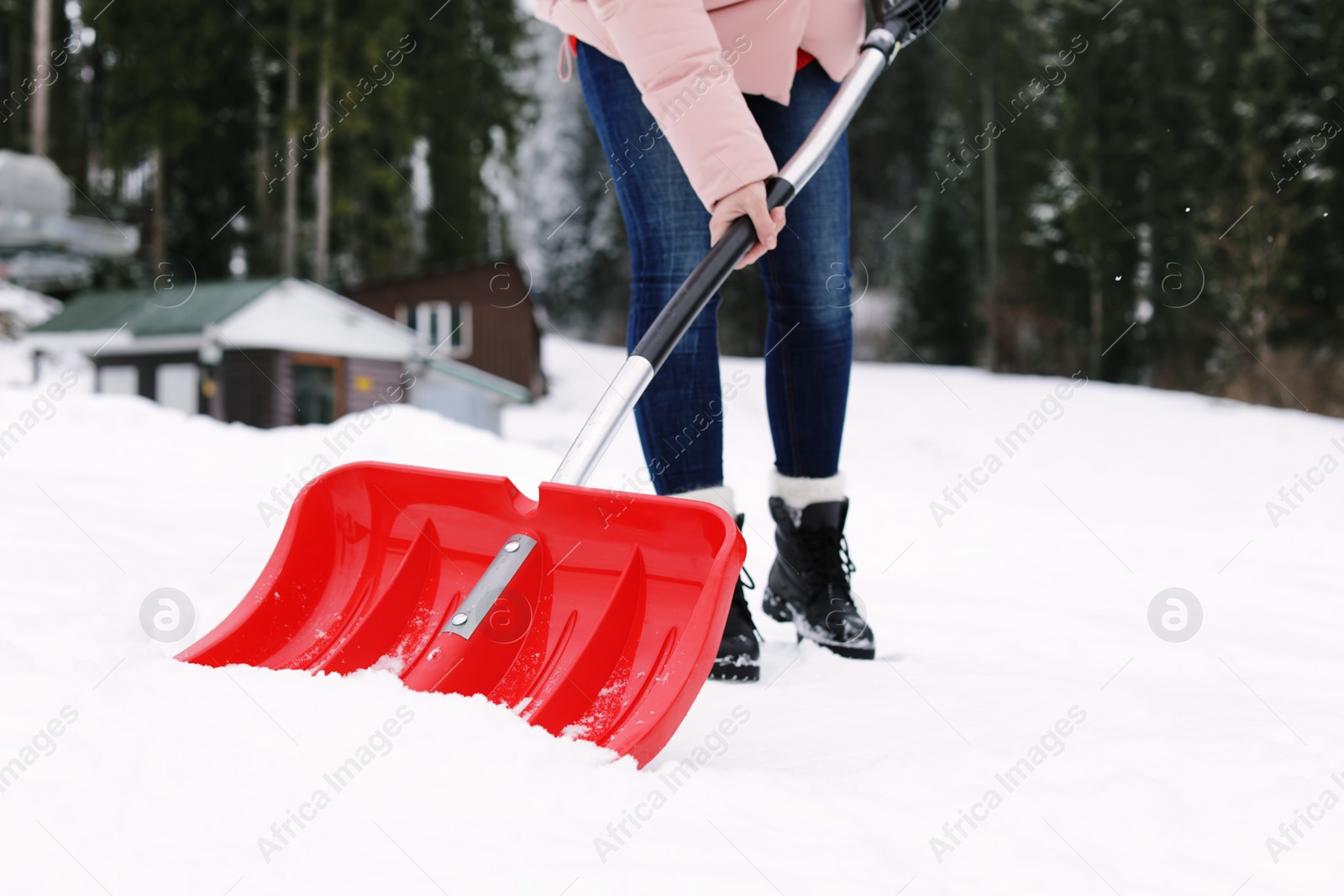 Photo of Woman removing snow with shovel near house