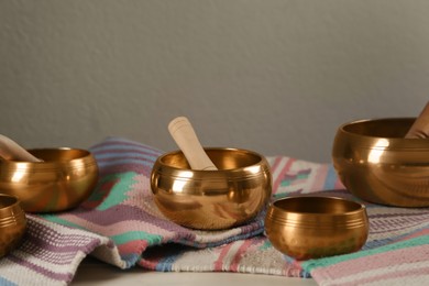 Photo of Tibetan singing bowls with mallets and colorful fabric on white table