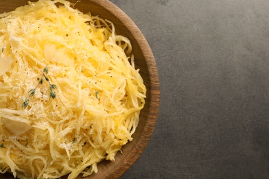 Photo of Bowl of cooked spaghetti squash on gray table, top view with space for text