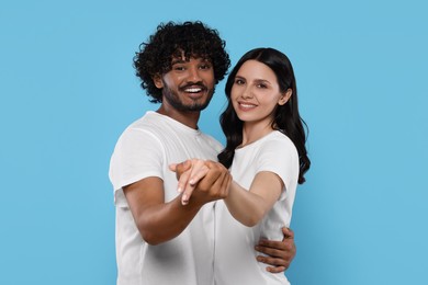 International dating. Happy couple dancing on light blue background