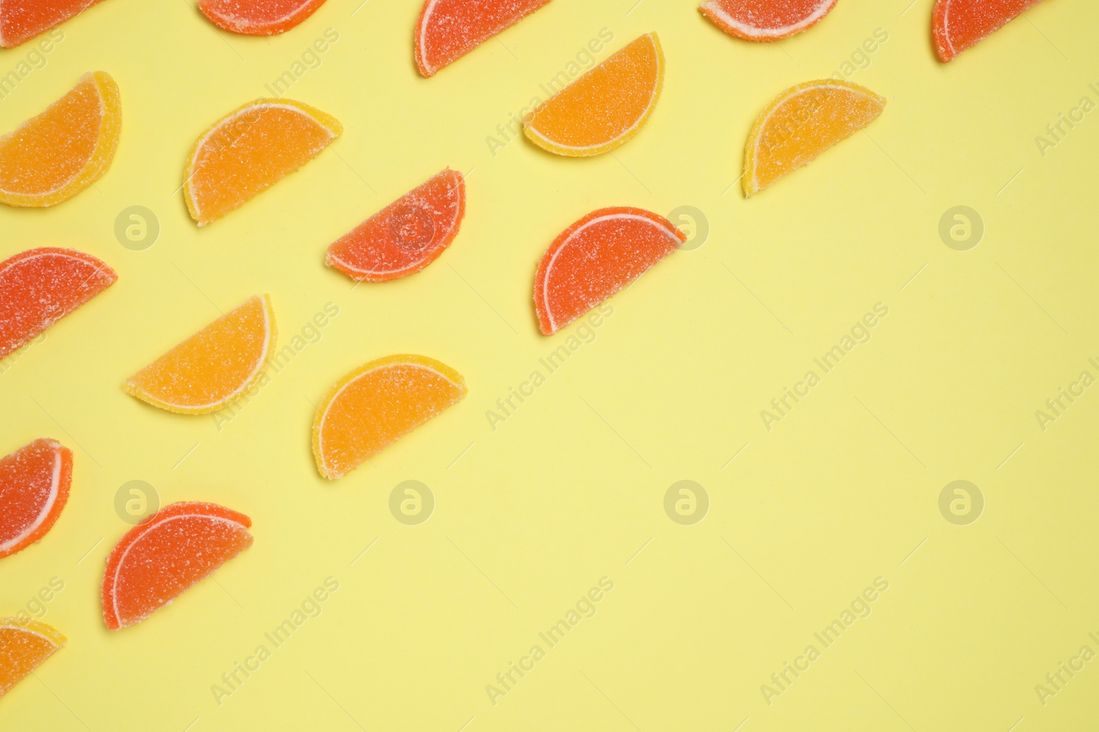 Photo of Many sweet jelly candies on pale yellow background, flat lay. Space for text