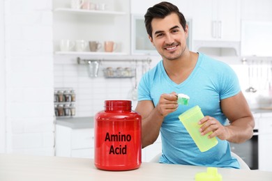 Image of Young athletic man preparing amino acids drink in kitchen