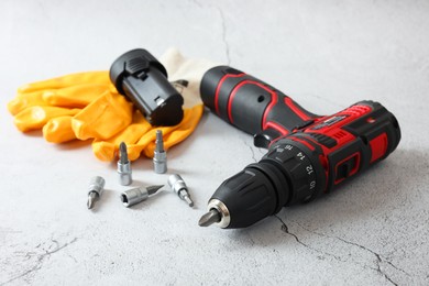 Electric screwdriver, drill bits, battery and gloves on light table