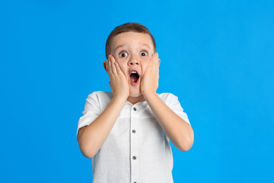 Photo of Portrait of emotional little boy on blue background