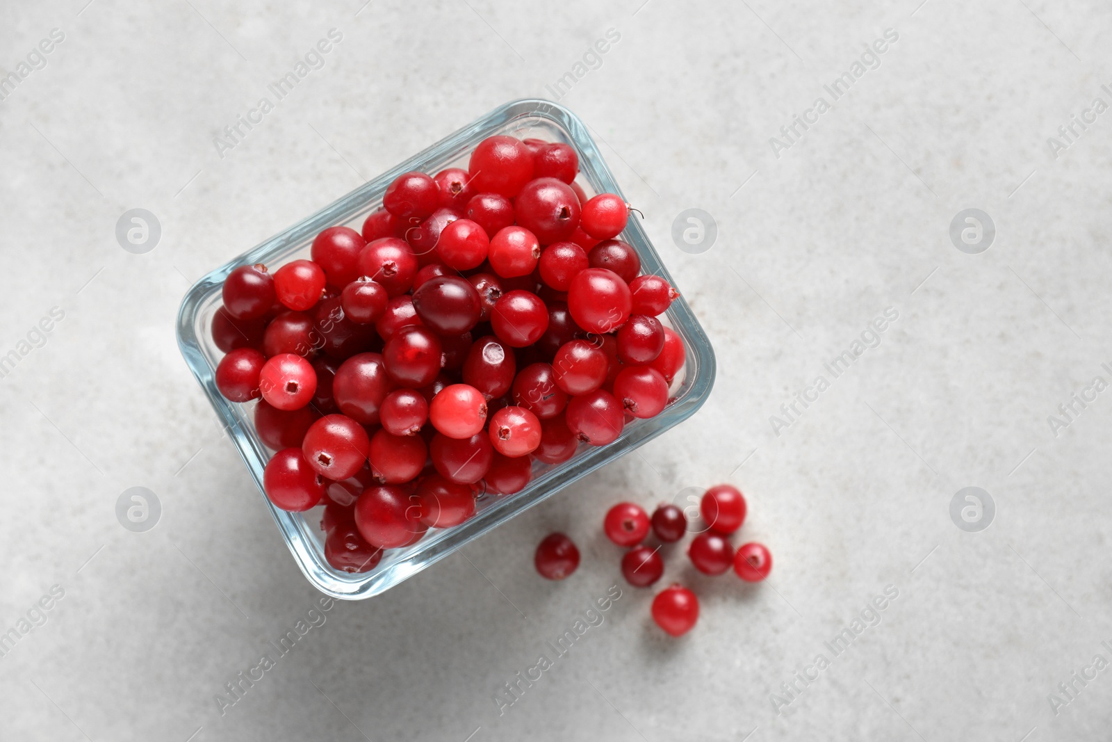 Photo of Cranberries in bowl on light grey table, top view. Space for text