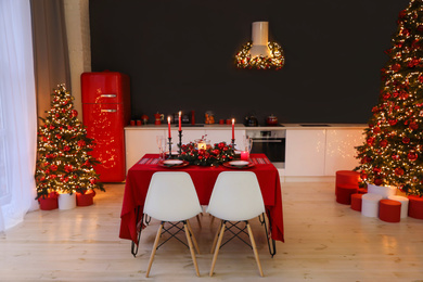 Stylish kitchen interior with festive table and decorated Christmas trees