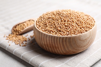 Mustard seeds in wooden bowl on table, closeup