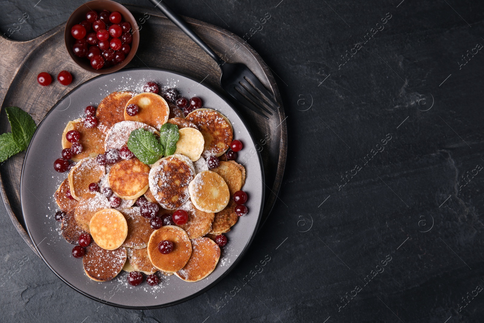 Photo of Cereal pancakes with cranberries served on black table, top view. Space for text