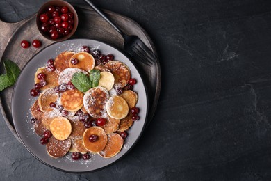 Cereal pancakes with cranberries served on black table, top view. Space for text