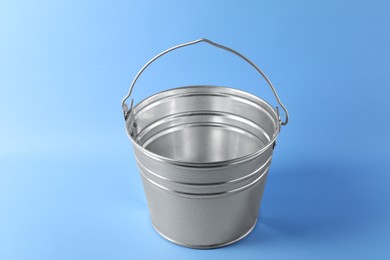 Photo of One shiny metal bucket on light blue background