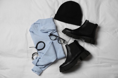 Photo of Stylish look with cashmere sweater, flat lay. Women's clothes and accessories on fabric