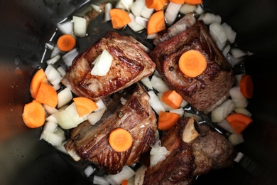 Photo of Top view of delicious pork ribs with vegetables in modern multi cooker, closeup