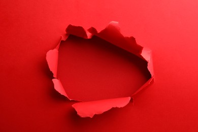 Hole in red paper on color background